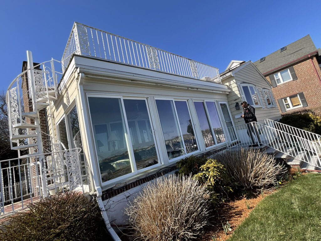 The rooftop deck in Lynn, MA, built by Monroy's Carpenters, Inc., features a stylish and secure design with an elegant white metal railing adorned with intricate patterns. IMG_0513