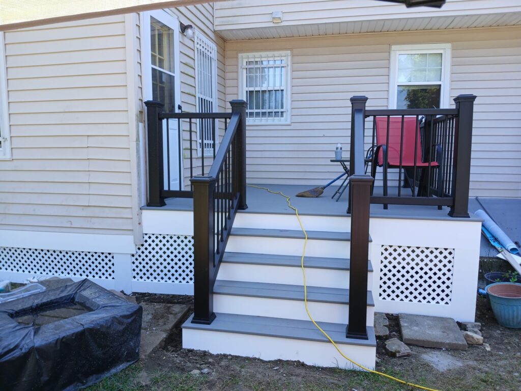 Black metal railings with horizontal balusters provide modern safety and unobstructed views, paired with matching gray steps leading to the white door.